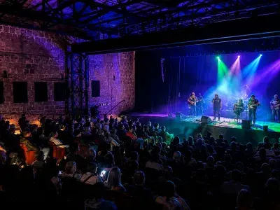 A crowd watches a live band perform under colorful stage lights inside the Tybee Post Theater.