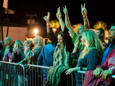 Concertgoers cheer with their hands raised during an outdoor nighttime performance at the Tybee Post Music Festival.