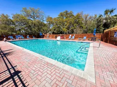 Outdoor swimming pool with lounge chairs and umbrellas surrounded by trees at River’s End Campground.