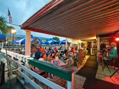 People eating at a restaurant outdoors while listening to a guitarist play live music.