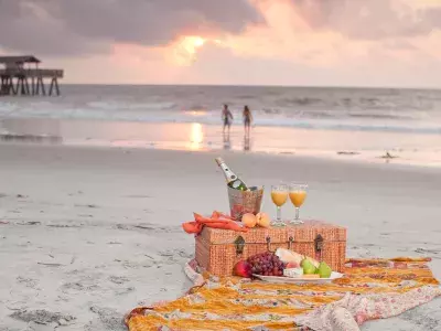 A picnic basket sitting on a blanket on the beach