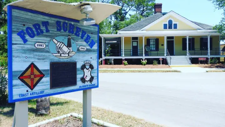 A sign that reads Forst Screven with a yellow historic building in the background.