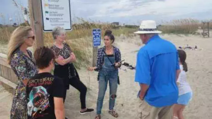 A beach guide directing a group on the beach