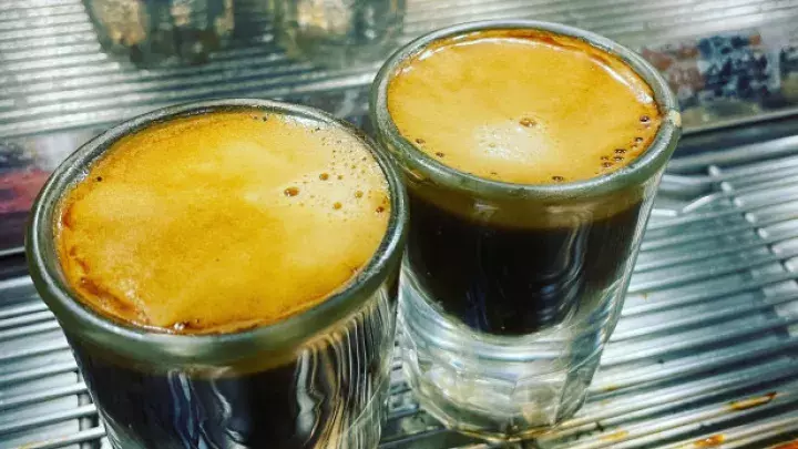 Two freshly brewed shots of espresso in small glass cups