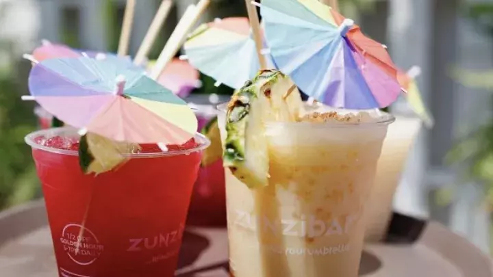 A tray of drinks with rainbow-colored mini umbrellas.
