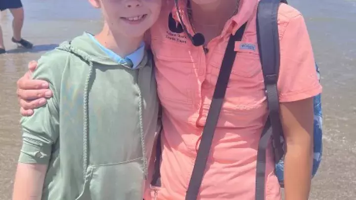 Child taking a photo with a Tybee Shark Teeth Tours guide on the beach