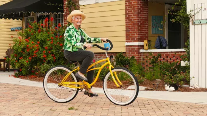 An older woman riding a yellow bike