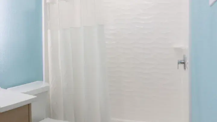 Spacious walk-in shower with white tile and glass doors.