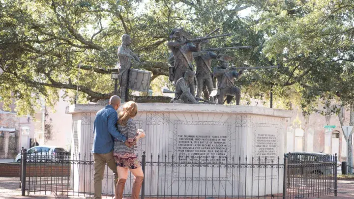 A couple with their backs turned, facing a monumental statue.