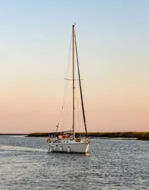 A sail boat on the ocean at sunset.
