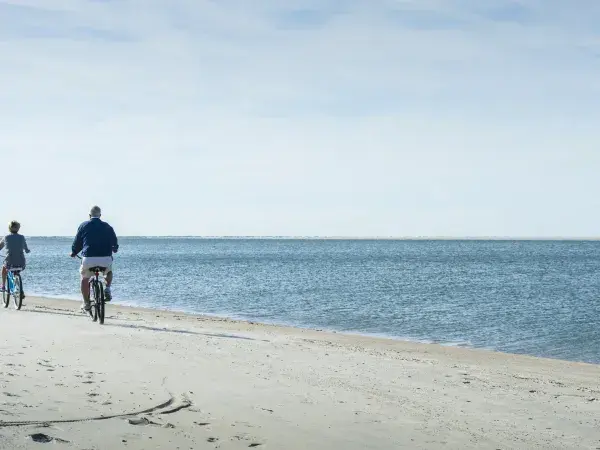 A family of two bike riding on the beach