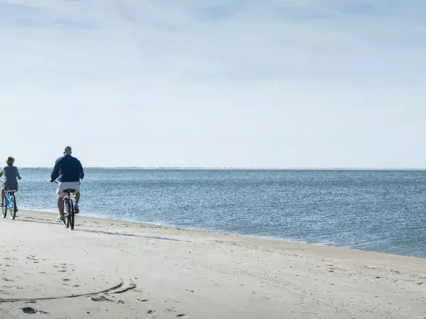 A family of two bike riding on the beach