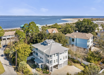 Aerial view of Oceanfront Cottage Rentals’ Tybee Oasis rental home with a view of the ocean, beach and blue sky
