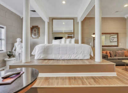 A Greek Mythology themed hotel suite with a large bed and white bedding.