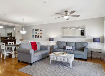 A spacious living room area with ample seating and a view of the kitchen