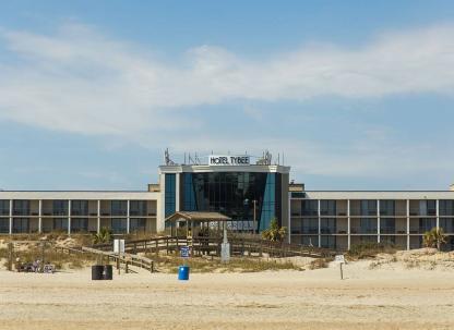 The front exterior view of a hotel on the beach.