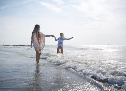 Mom and daughter on the beach playing in the ocean.