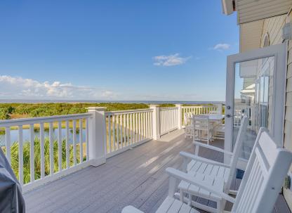 An expansive outdoor balcony overlooking marshland and a dock.