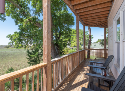 Sunset Hammock rental balcony overlooking Tybee Island’s serene marshes with Adirondack chairs.