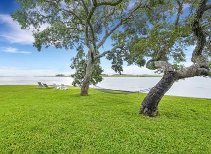 Waterfront lawn at Horsepen Cottage by Coastline Concierge, featuring live oak trees, a hammock and views of the tidal river.