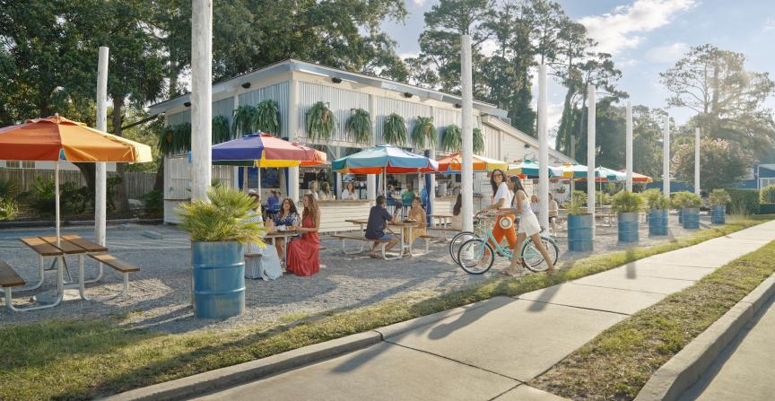 People eating outdoors at a restaurant with colorful rainbow umbrellas.